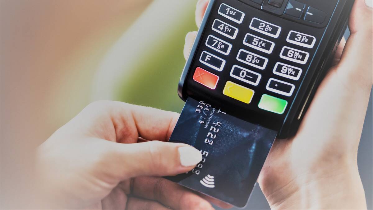 A close shot of someone putting their credit card into the chip slot of a payment machine.