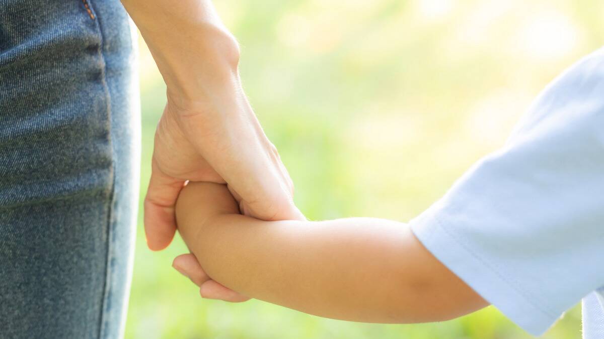 A close shot of a mother holding her young child's hand.