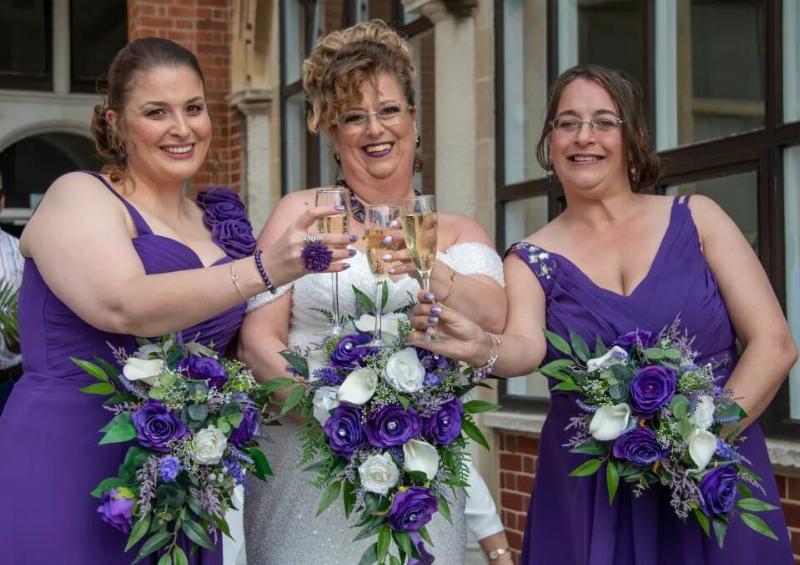 WIlkinson with her two bridesmaids, who are in matching shades of purple.