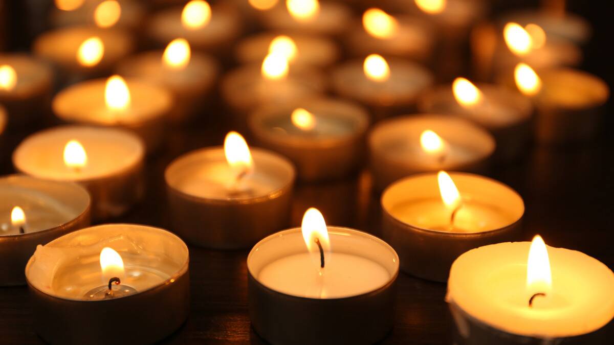 A collection of tea light candles, all lit, on the ground.