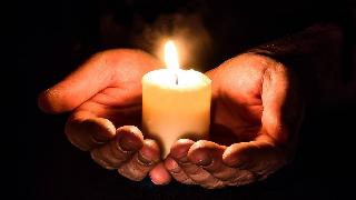 A close shot of a pair of cupped hands holding a candle.