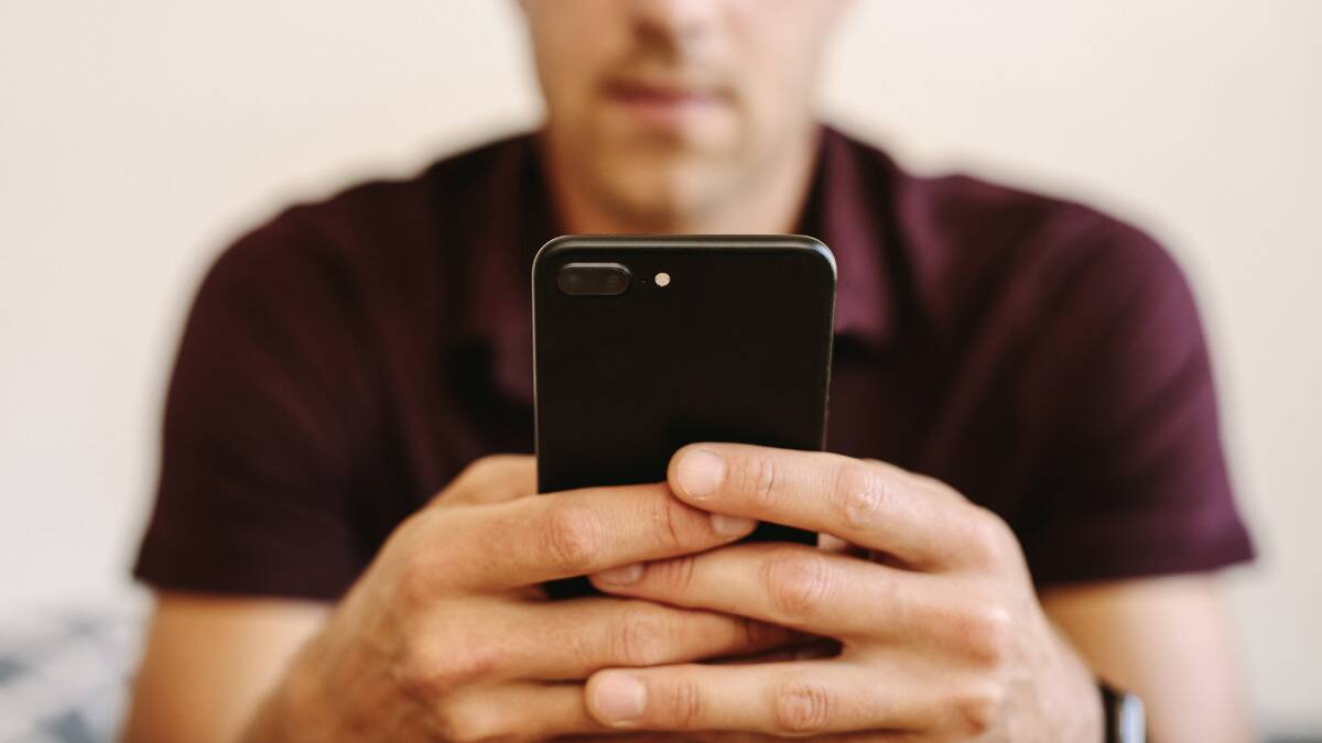 A man holding his phone out in front of him with both hands.