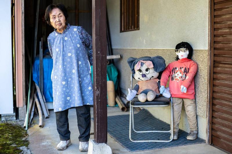 This photo taken on October 21, 2024 shows Hisayo Yamazaki standing next to the puppets outside her house in the village of Ichinono in the city of Tamba-Sasayama, Hyogo Prefecture.