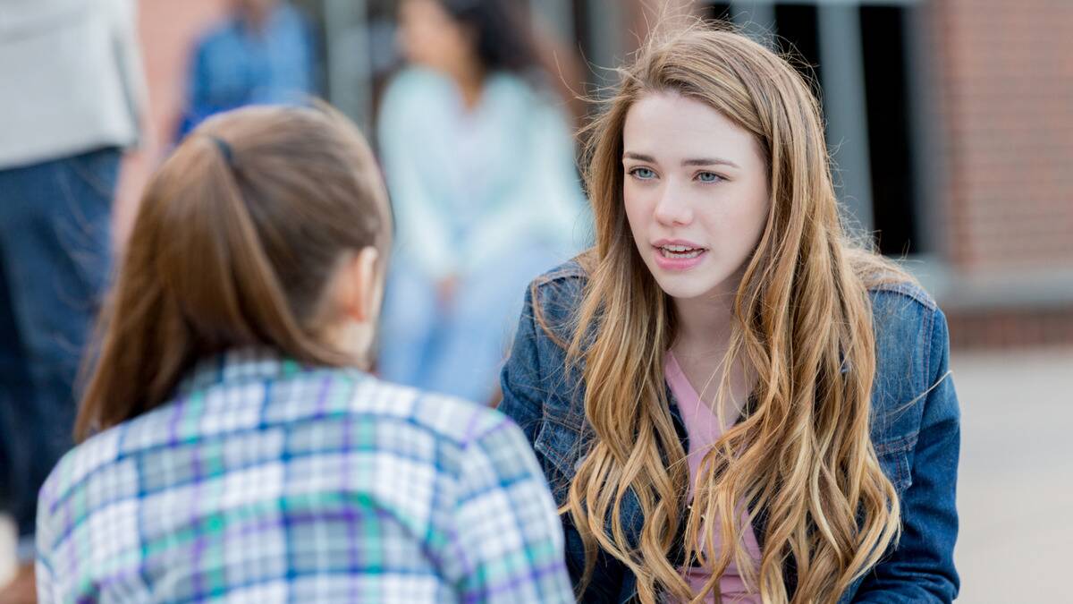 A woman speaking to a friend with an incredulous expression.