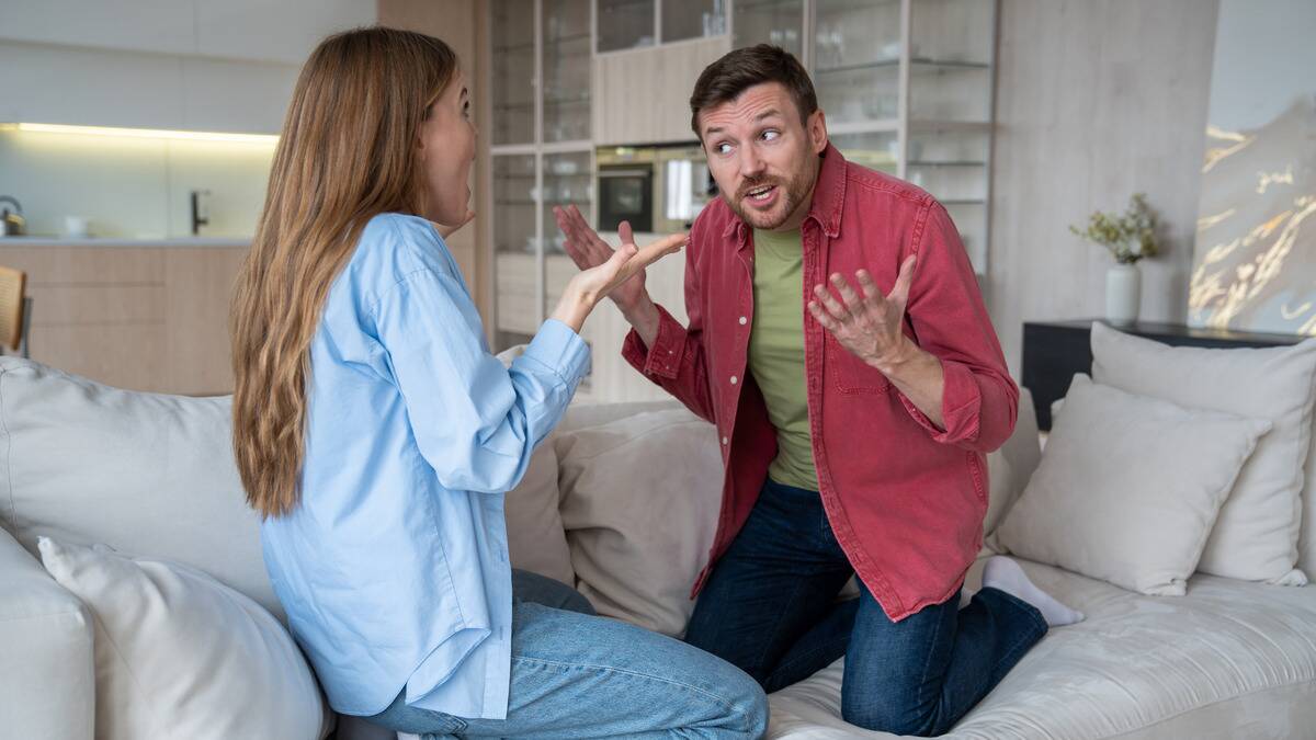 A couple fighting as they sit on the couch.