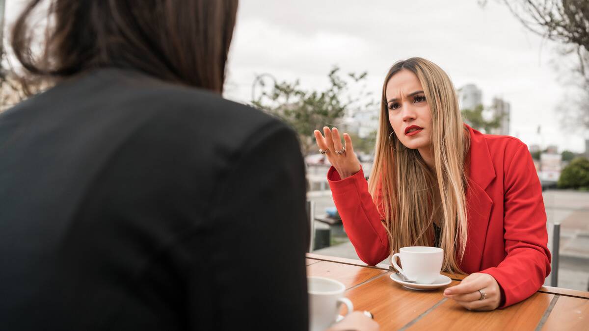 A woman looking incredulously at her friend who she's speaking to.