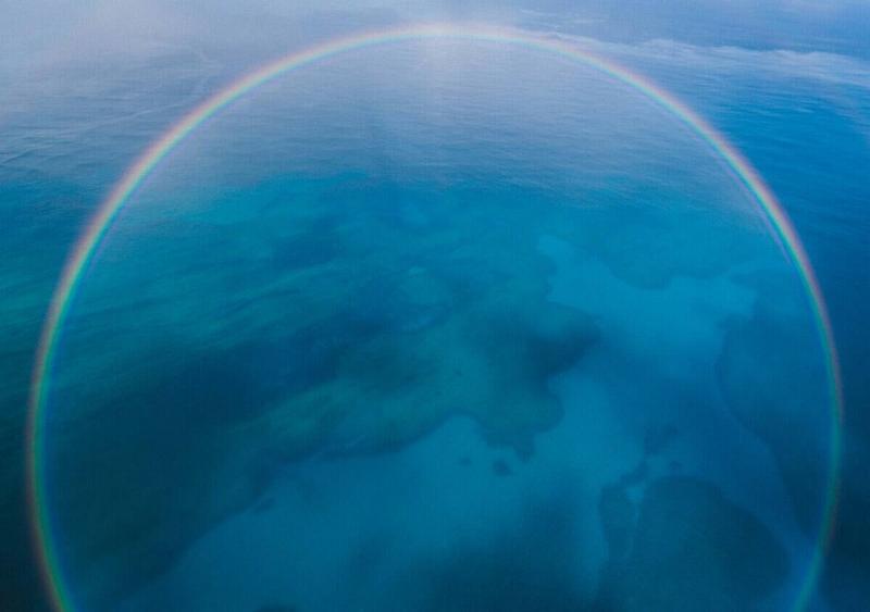 A circular rainbow shining over the ocean.