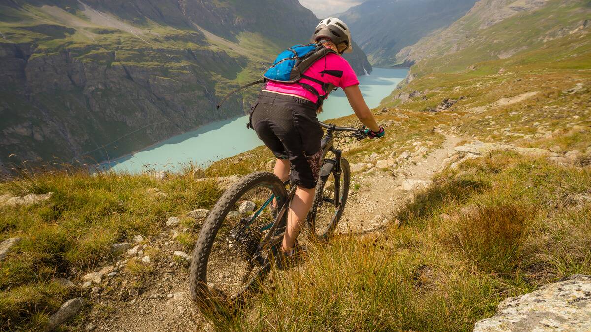 A photo from behind of someone mountain biking in a valley.