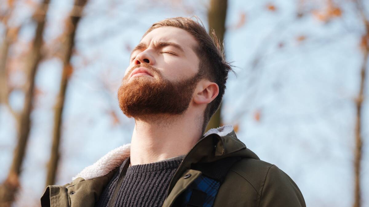 A man standing outside with his head tilted up, eyes closed.