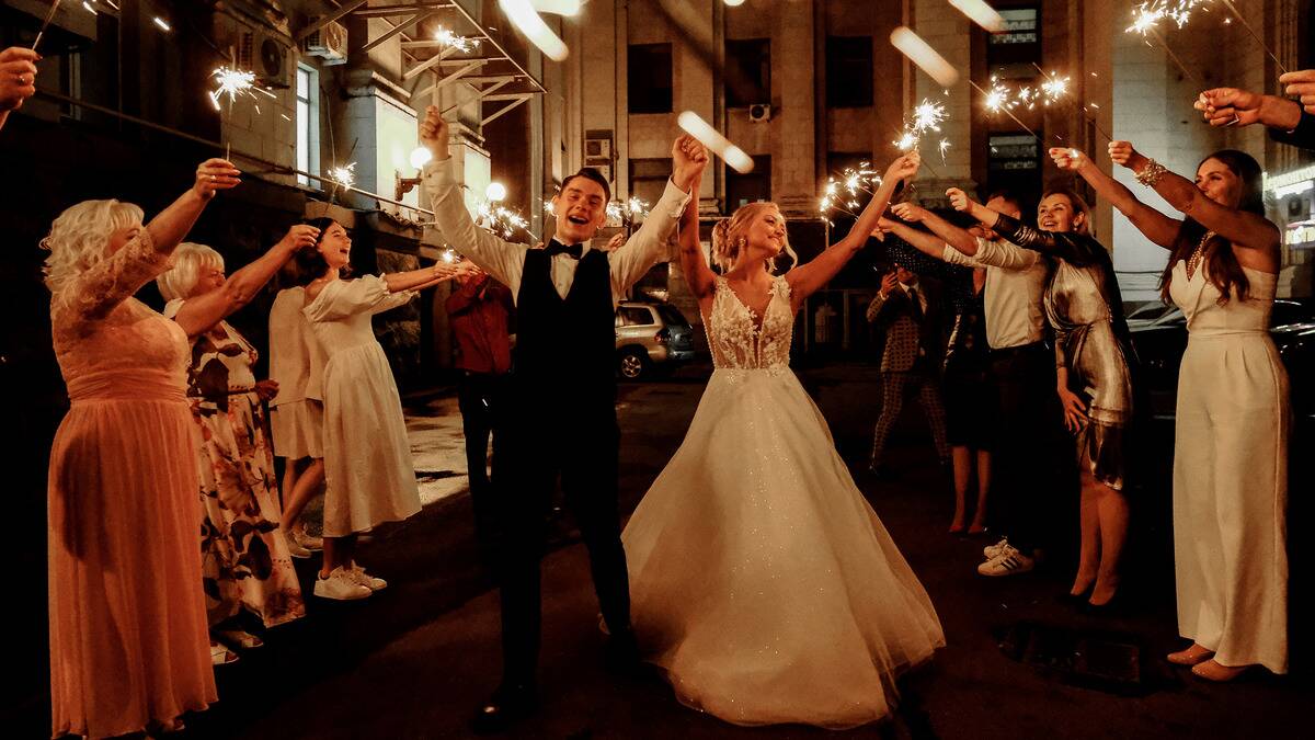 A just-married couple walking beneath rows of sparklers held up by their wedding guests.