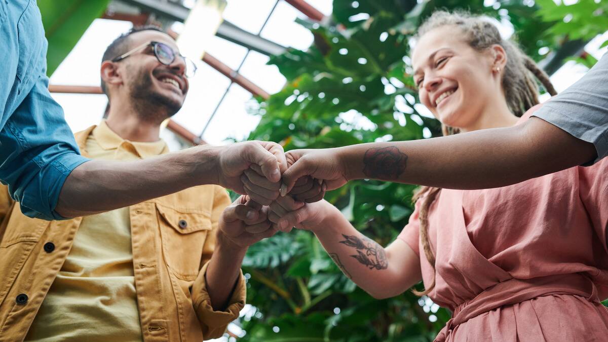 A low-angle shot of four friends fist-bumping in a circle.