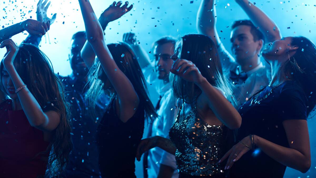 A group of people dancing in a club as confetti rains down on them.