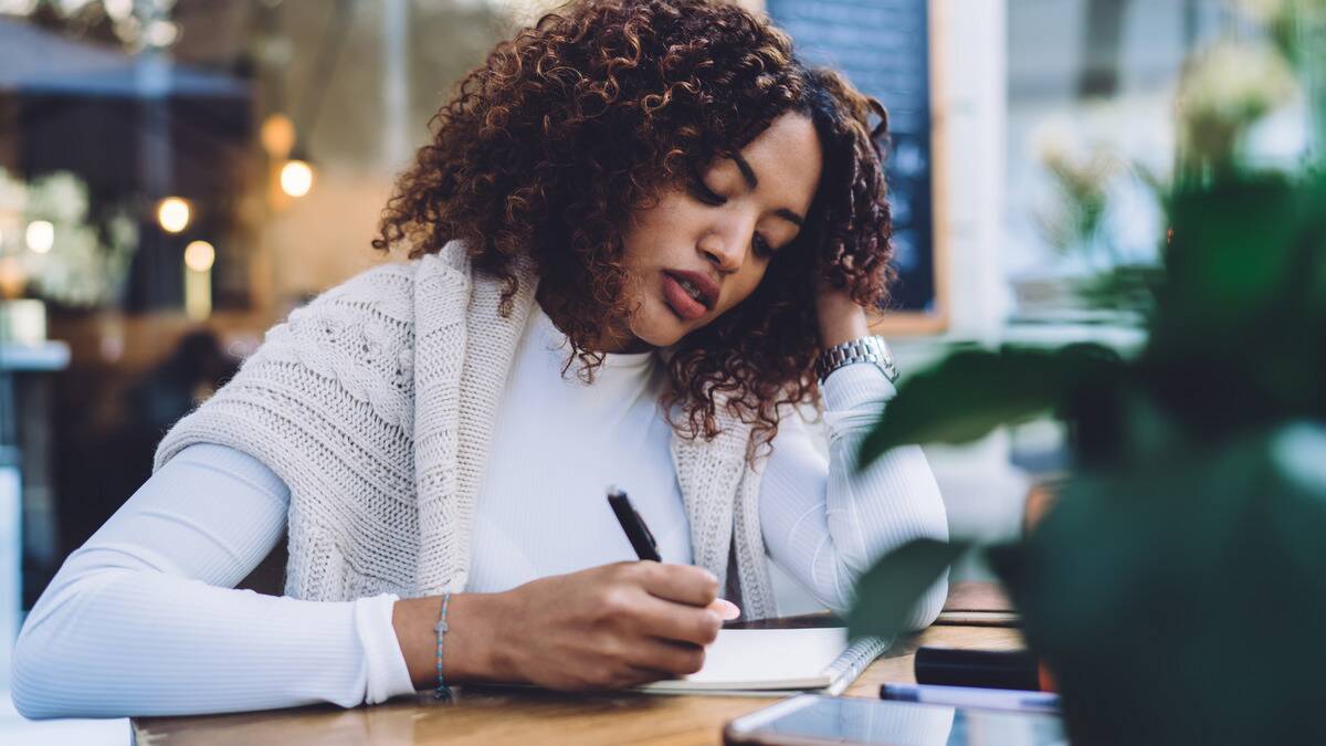 A woman sitting at a table taking notes.