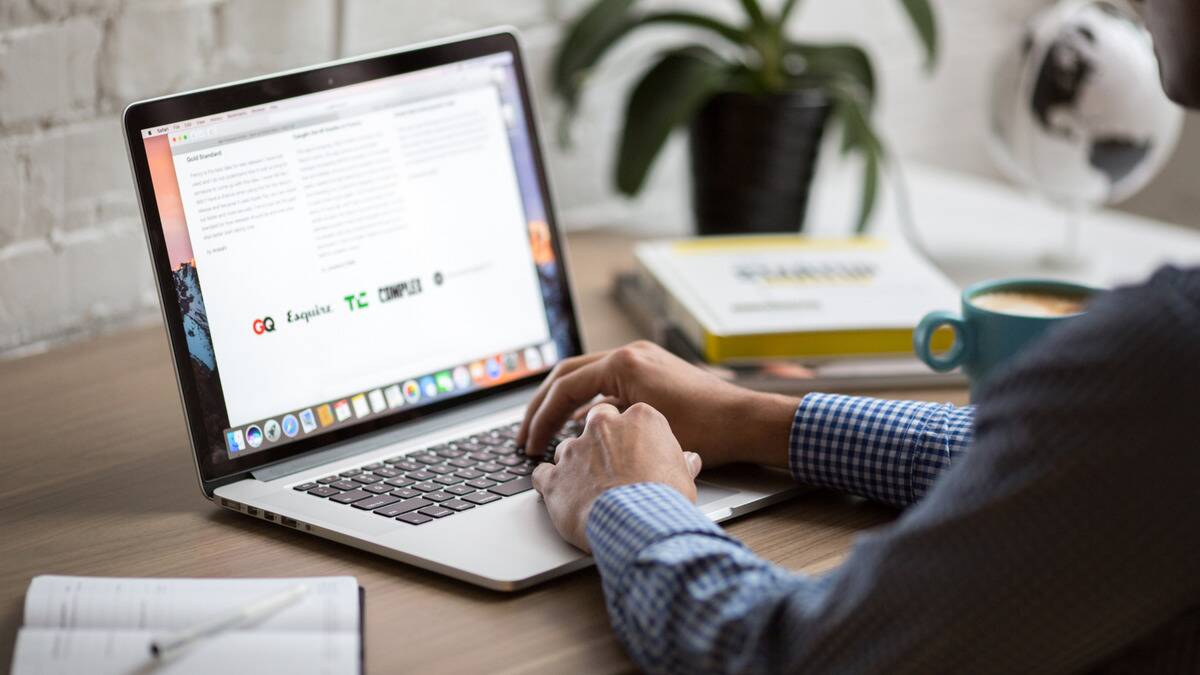 A laptop open and a pair of hands typing away on the keyboard.