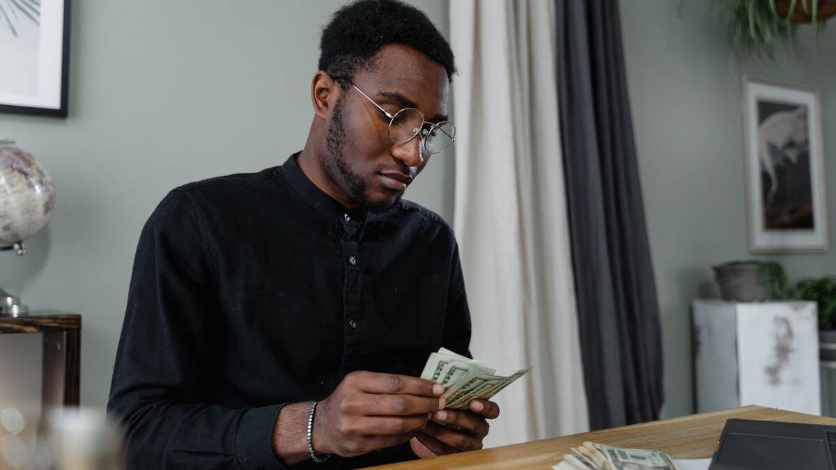 A man sitting at a table counting a stack of bills.