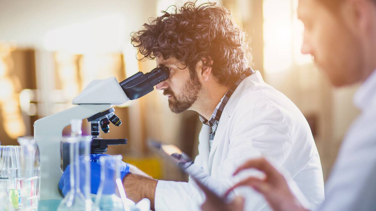 A scientist looking into a microscope.