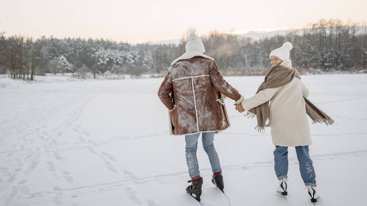 A couple skating outdoors together, the woman looking over her shoulder at the camera.