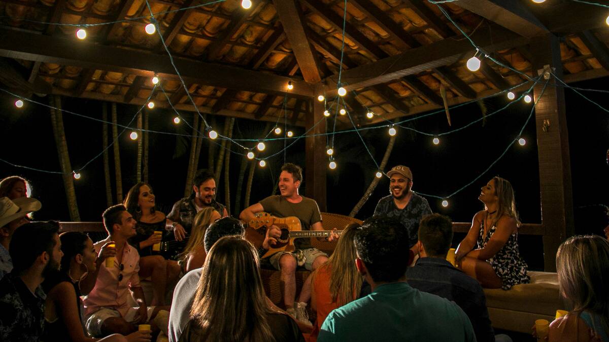 A group of friends all sat under a gazebo at night during a party.