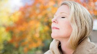 A close shot of a woman who's standing with her eyes closed outside, head tilted upward slightly.