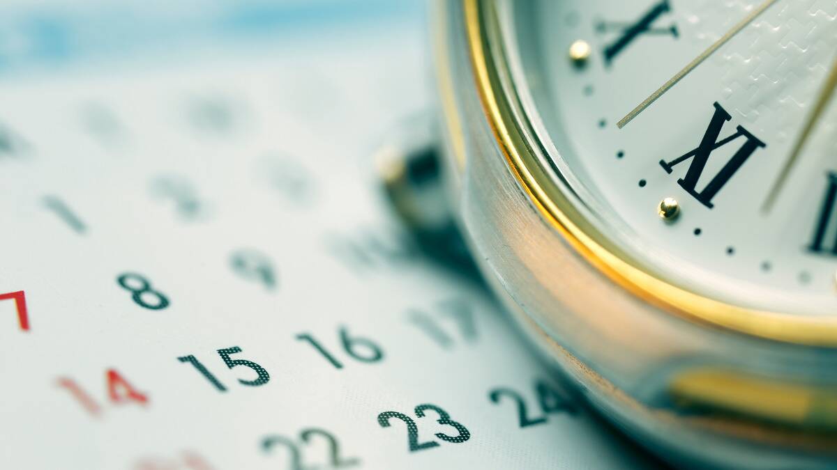 A close photo of a calendar and a clockface.