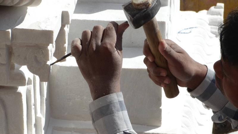 A close shot of someone chipping away at stone, sculpting something.