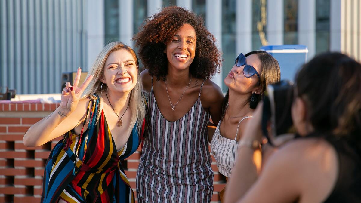 Three friends smiling and posing for a photo together.