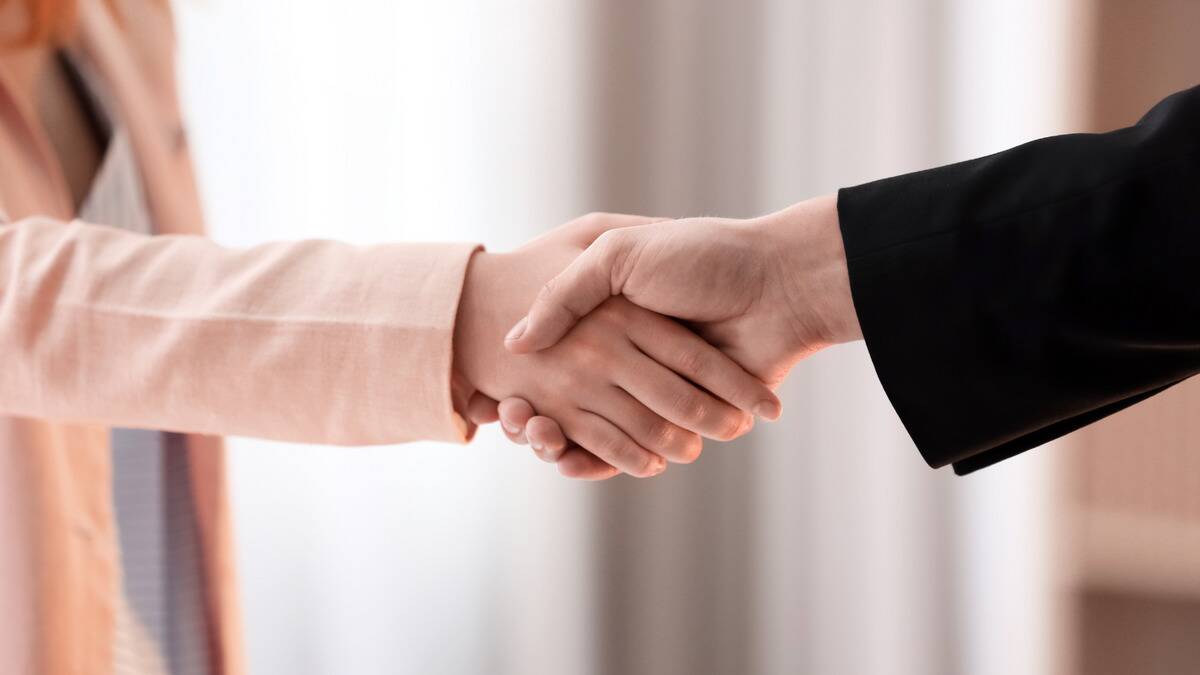 Two hands, both presumably in business wear, shaking hands.