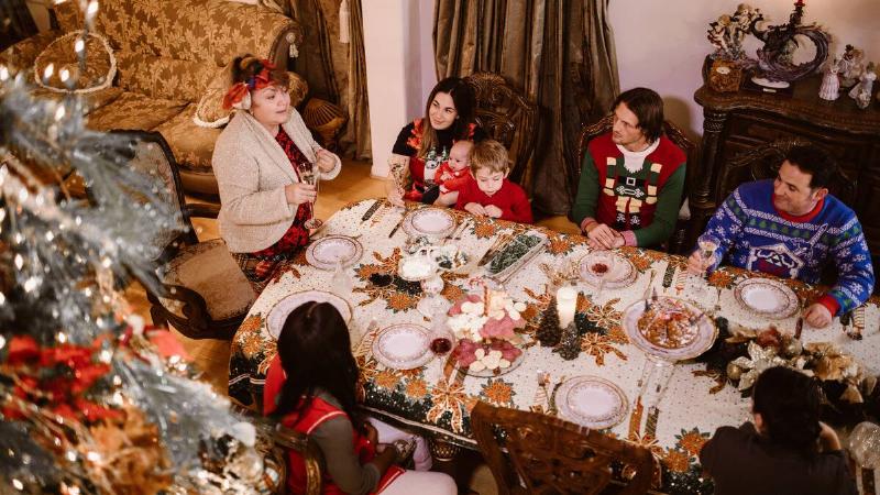 An above-angle shot of a family around a large table for Christmas dinner.