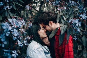 couple smiling touching foreheads surrounding by blooming tree