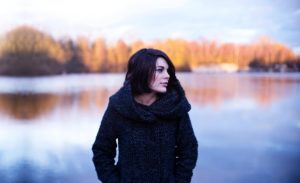 woman stands in fall weather with hands in her coat pocket