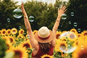 woman in field of sunflowers and bubbles