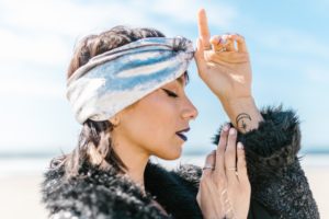 woman with headband doing the third eye at the beach