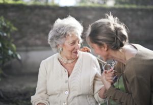 woman and grandma talk while holding hands on a bench