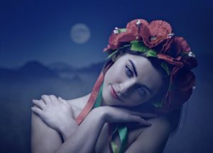 woman looking down and hugging herself while wearing flower crown