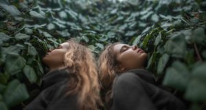 woman and her clone with eyes closed by leaves