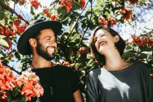 man and woman stand under floral trees smiling