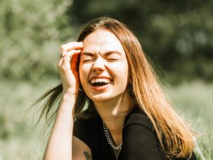 woman laughing while sitting on grass