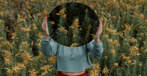 woman holding up mirror reflecting field