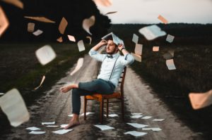 man with books falling over him