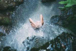 woman standing under waterfall