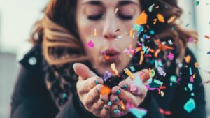 woman blows confetti out of her hand