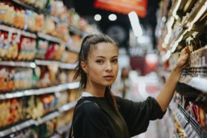 woman looks to camera in grocery store aisle