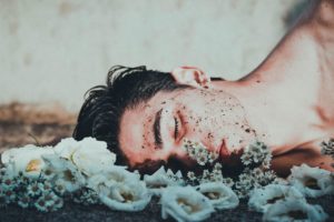 man laying in a bed of flowers with dirt all over his face