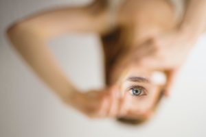 woman holds her eye reflection in piece of glass