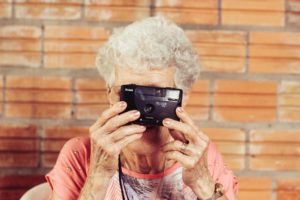 old woman holds up camera