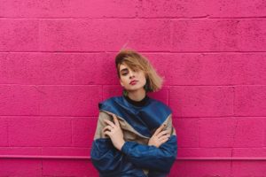 woman crosses hearms by pink wall