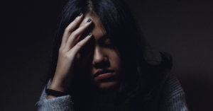 woman sits with her hand on her head looking down