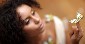 unfocused woman holding yellow butterfly on her finger in focus