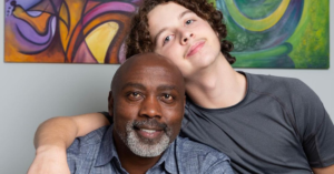 peter and his adopted son pose for picture as his son leans on him and wraps his arm around him