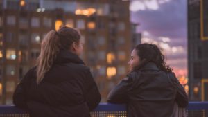 two girls stand in front of bridge